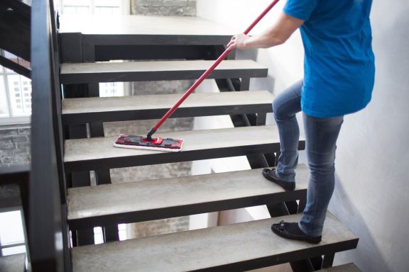 Treppenhausreinigung Eine Person wischt mit einem Mopp die Stufen einer Treppe.